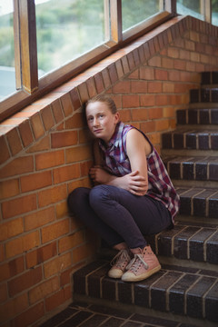 女学生独自坐在学校的楼梯上