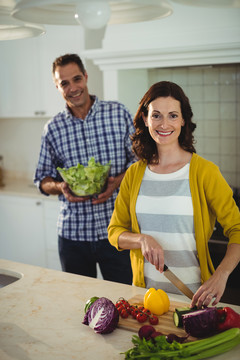 微笑的夫妇在家里的厨房里切菜