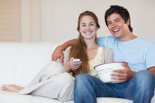 一对夫妇在客厅吃爆米花时看电视