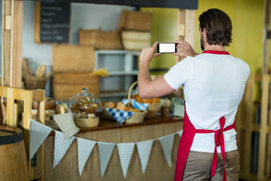 面包店员工在烘焙店柜台使用手机