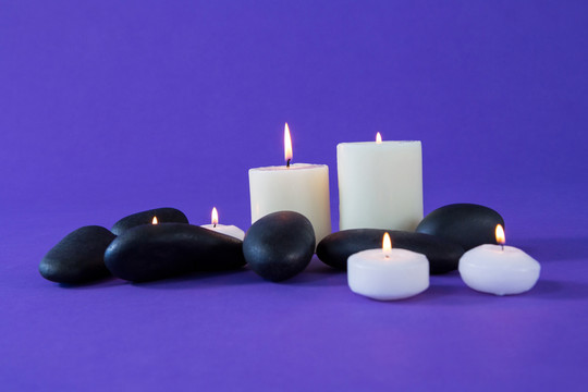 在紫色背景上点燃蜡烛和禅石