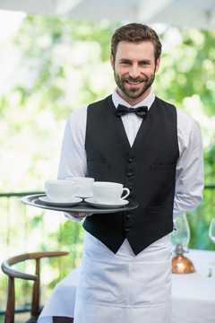 餐厅男服务员端着咖啡杯托盘