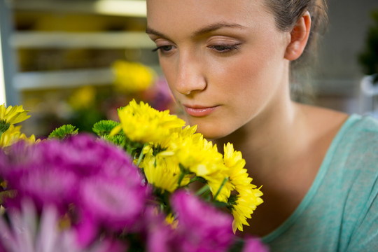 在花店里闻到一束花的女人