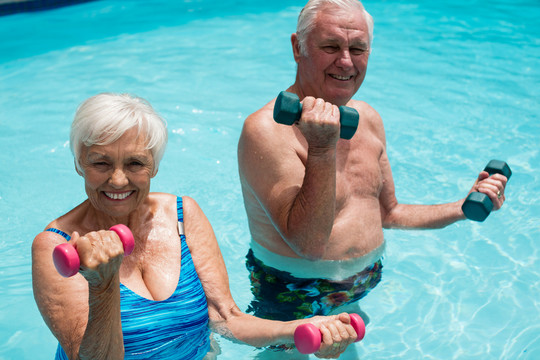 老年夫妇在游泳池里用哑铃锻炼