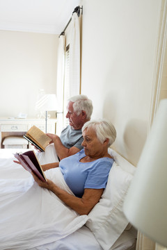 老年夫妇在家里卧室看书