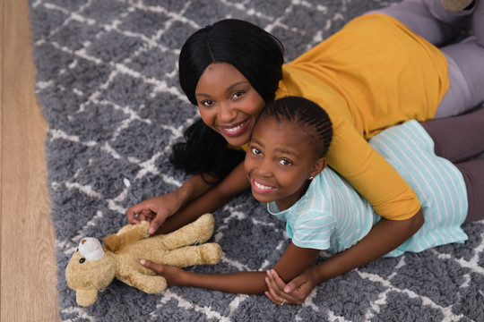 地毯上抱着玩具熊的母女