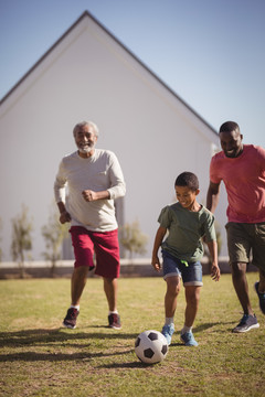 男孩与他的父亲和孙子踢足球