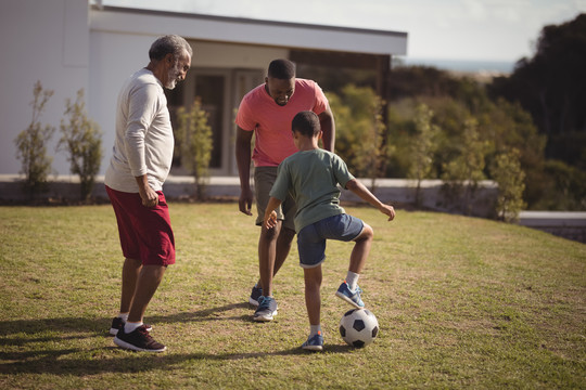 男孩和他的父亲和孙子踢足球
