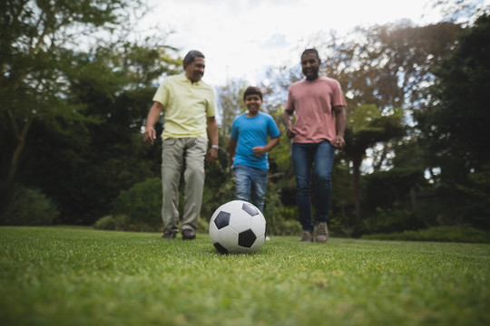 多代家庭在公园球场上一起踢足球