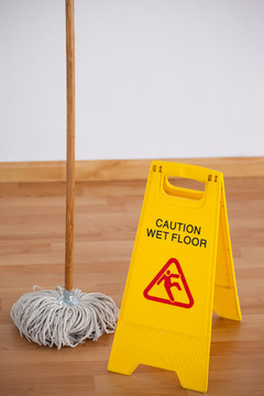 木地板上带湿地板警示标志的拖把