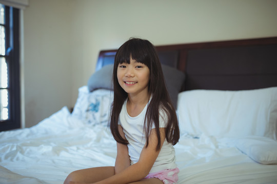 微笑的女孩坐在卧室的床上