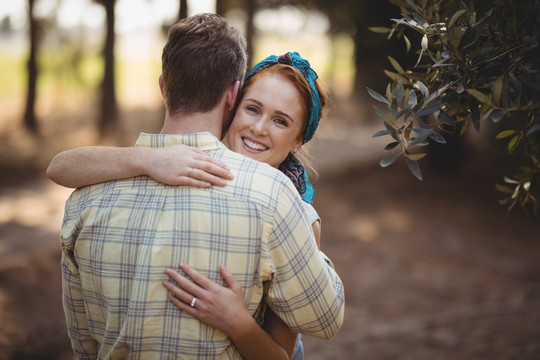 在橄榄农场拥抱的年轻夫妇