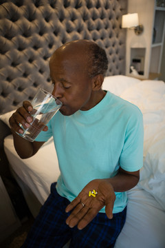 在卧室喝水时拿药的老人