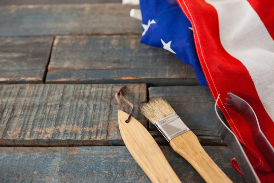 木桌上贴美国国旗的刷子和钳子