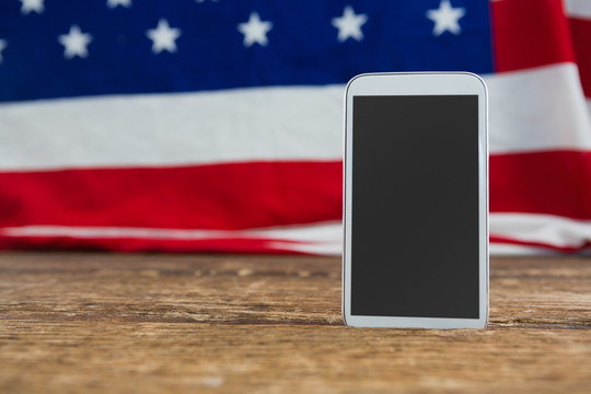 木桌上摆放的美国国旗和手机