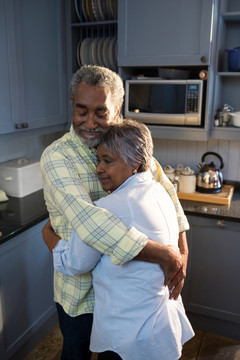 在厨房里拥抱的老年夫妇