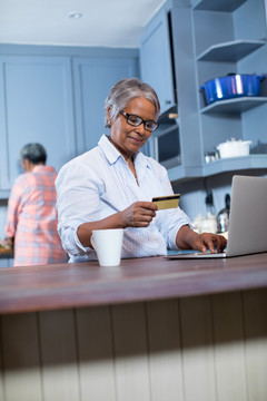 女人在家里网上购物时使用信用卡