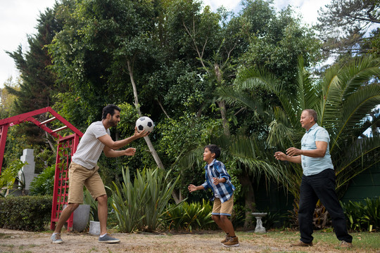 快乐家庭在公园和植物踢足球