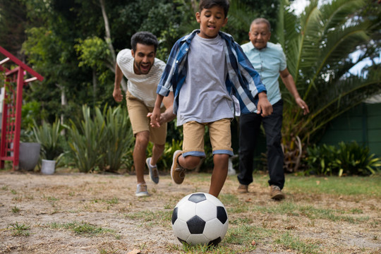 男孩和家人在院里踢足球