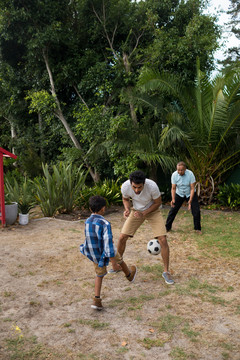 男孩在院子里和父母一起踢足球