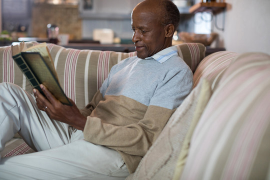 老人在家客厅沙发上休闲看书