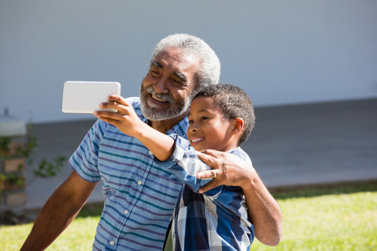 爷爷和孙子在后院用手机自拍