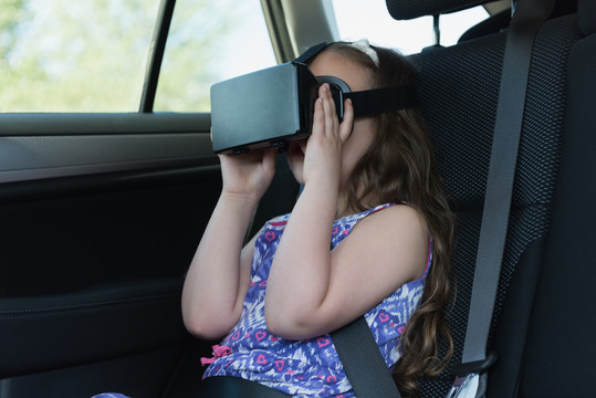小女孩在车上使用虚拟现实耳机