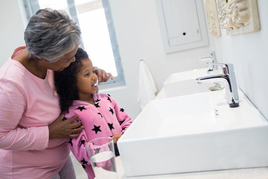 在浴室里帮孙女刷牙的奶奶