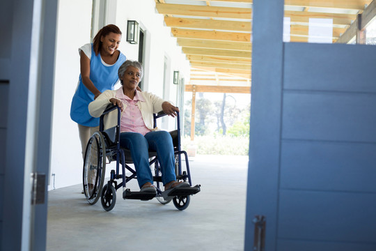 女医生推着老年病人坐在轮椅上