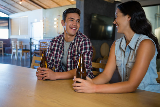 微笑的朋友们在酒吧柜台喝啤酒