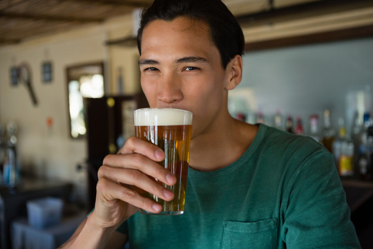 在酒吧喝啤酒的年轻人的肖像
