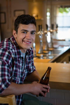 在酒吧柜台喝啤酒的年轻人