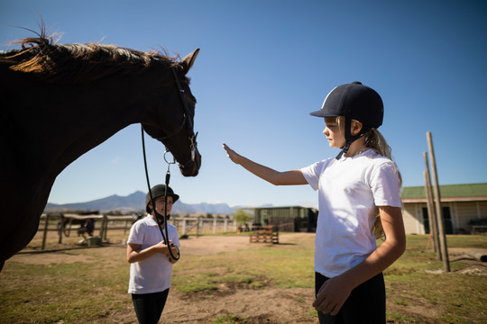 两个女孩牵着一匹马站在牧场上