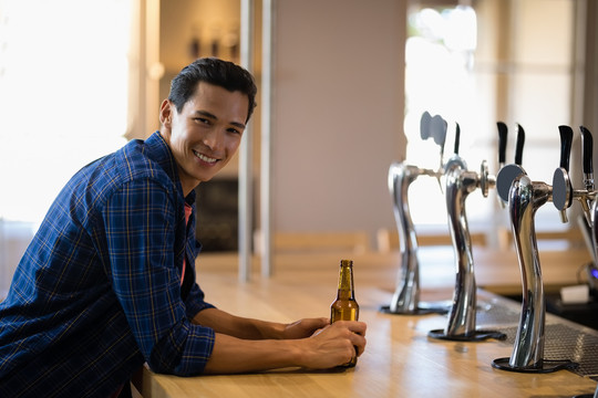 酒吧柜台上喝啤酒的男人的画像