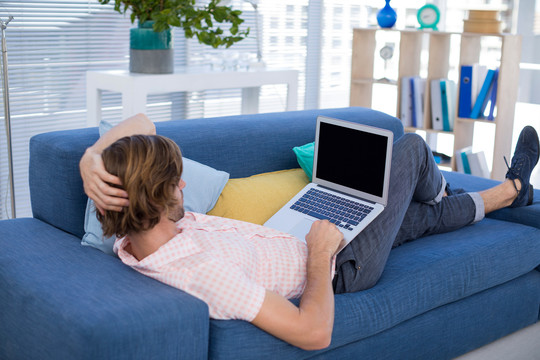 男性主管在沙发上休息时使用电脑