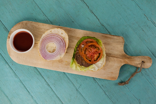 木桌切肉板上的汉堡包和酱汁