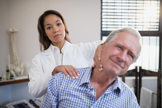 女治疗师为老年男性患者按摩颈部