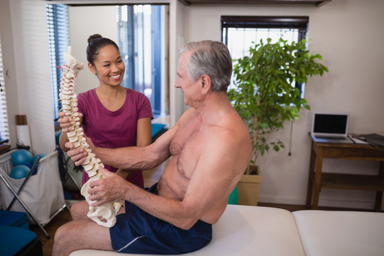 治疗师看着患者托着人造脊柱