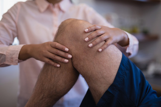 女性治疗师与老年男性患者膝关节