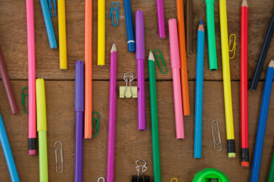 木桌上各种颜色的铅笔和回形针
