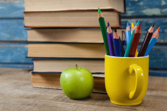 木桌上的彩色铅笔和苹果