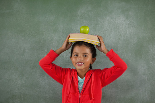 小女孩把书和苹果放在头上