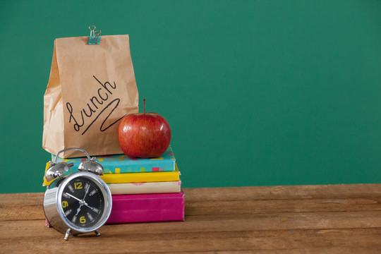 午餐纸袋和书堆上的苹果