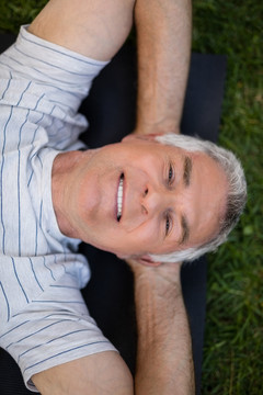 躺在运动垫上休息的微笑老人
