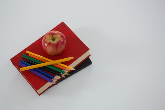 白底书上的苹果和彩色铅笔