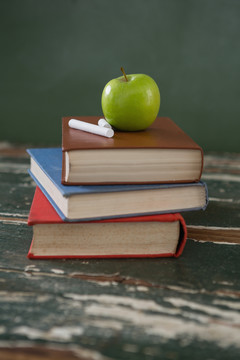 一堆书上的苹果和粉笔