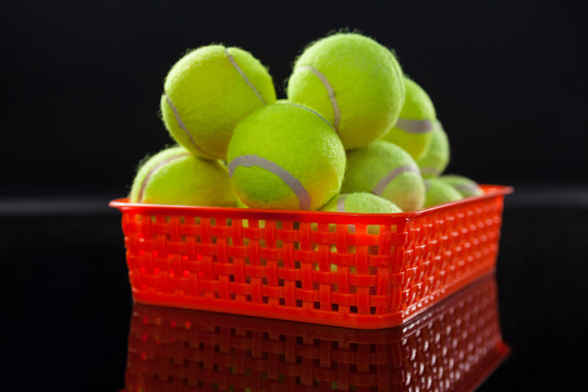 荧光黄网球在红色塑料篮中反射