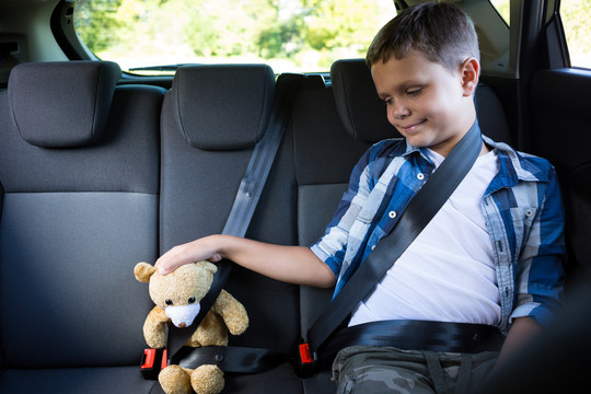 小男孩和泰迪熊坐在汽车后座上
