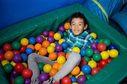 快乐的男孩躺在彩色的球里