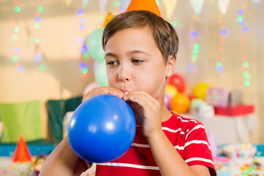 生日派对上吹气球的可爱男孩